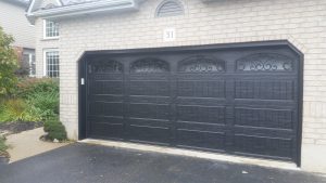 Black Clopay Classic door with elegant long panels and wrought iron arch window inserts