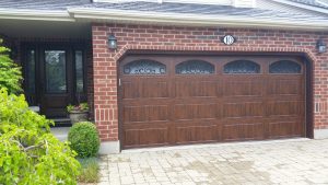 Walnut oak Clopay Gallery door with elegant long panels and wrought iron arched windows