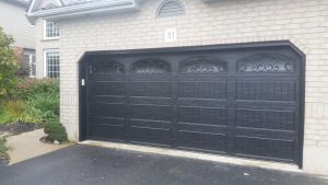 Black Clopay Classic door with elegant long panel and wrought iron arched window inserts