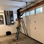Garage door technician repairing a high-tension spring on a garage door.