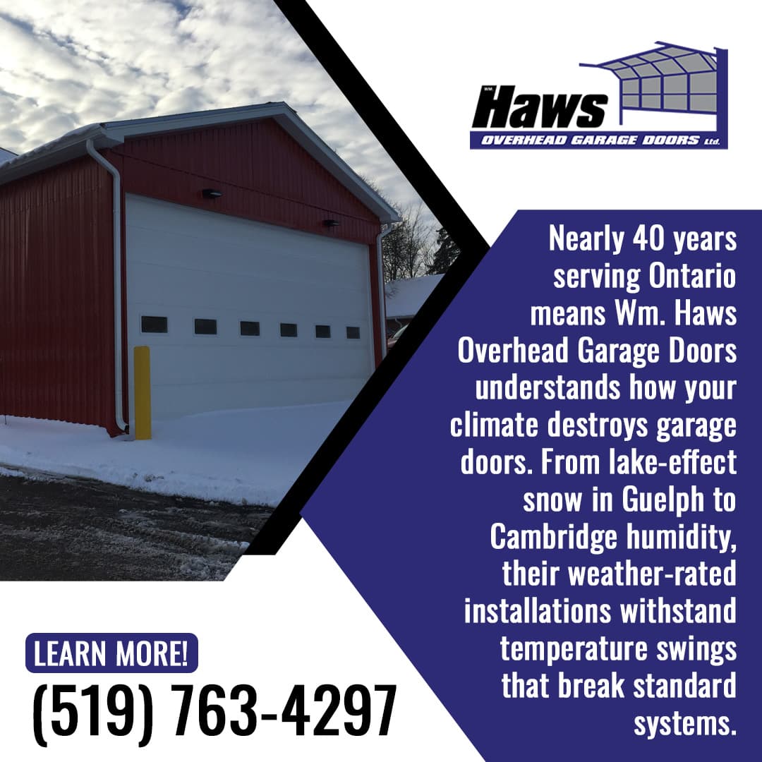 A red-sided commercial or detached garage building with a wide white sectional garage door in a snowy setting.