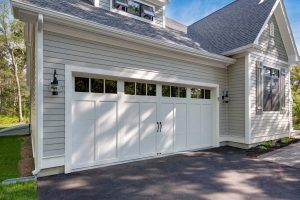 White carriage-style garage door installed on a modern suburban home exterior