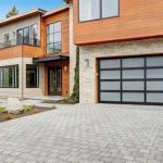 Contemporary house exterior with a sleek glass-panel garage door and paved driveway.