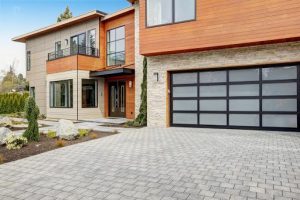 Contemporary house exterior with a sleek glass-panel garage door and paved driveway.