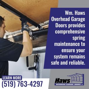 Technician adjusting garage door torsion spring system for maintenance and safety