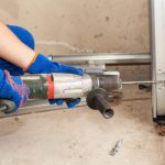 Technician using a drill to install or repair garage door track hardware