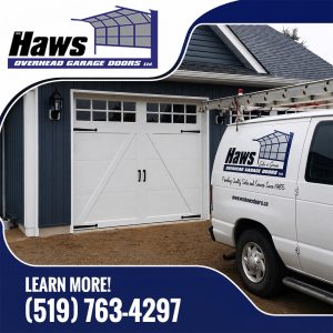 White Haws Overhead Garage Doors service van with ladder parked in the driveway in front of an installed white carriage-house style garage door on a blue home.