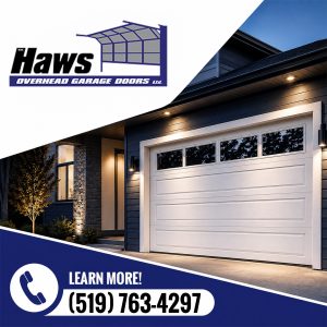 Exterior view of a modern dark-sided home at night with exterior lighting highlighting an installed white garage door with upper glass windows.