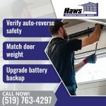 Garage door service technician using a winding tool to adjust an overhead torsion spring above a residential garage door panel.
